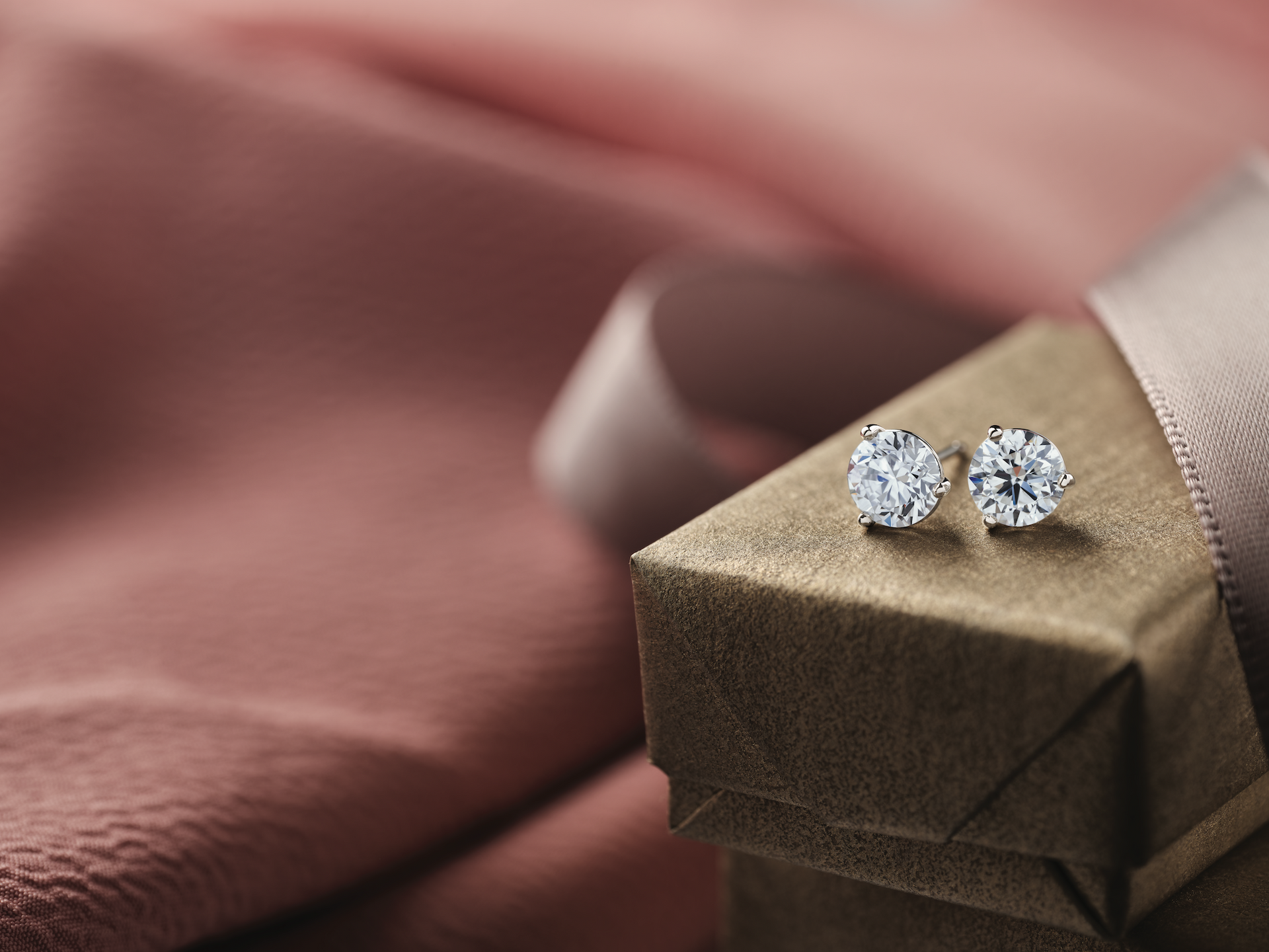 A pair of diamond stud earrings are sitting on top of a gift box.