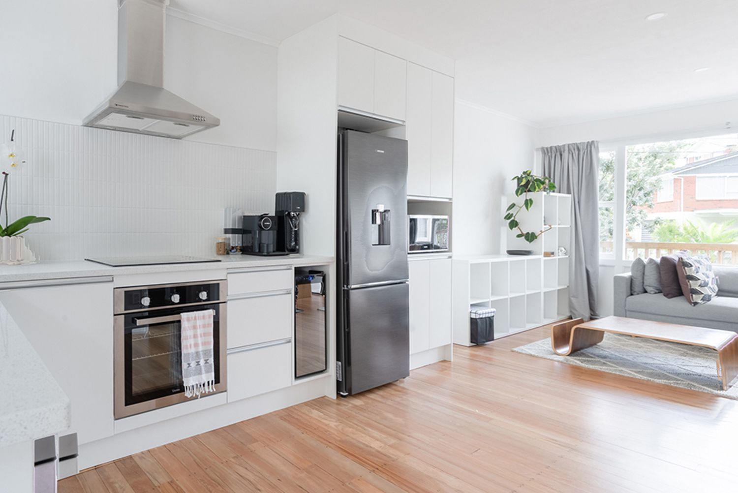 A kitchen with a stainless steel refrigerator and a stove top oven. Modern kitchen and living