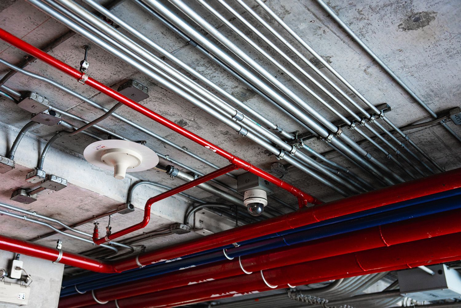 A bunch of pipes are hanging from the ceiling of a building. A bunch of pipes are hanging from the ceiling of a building.