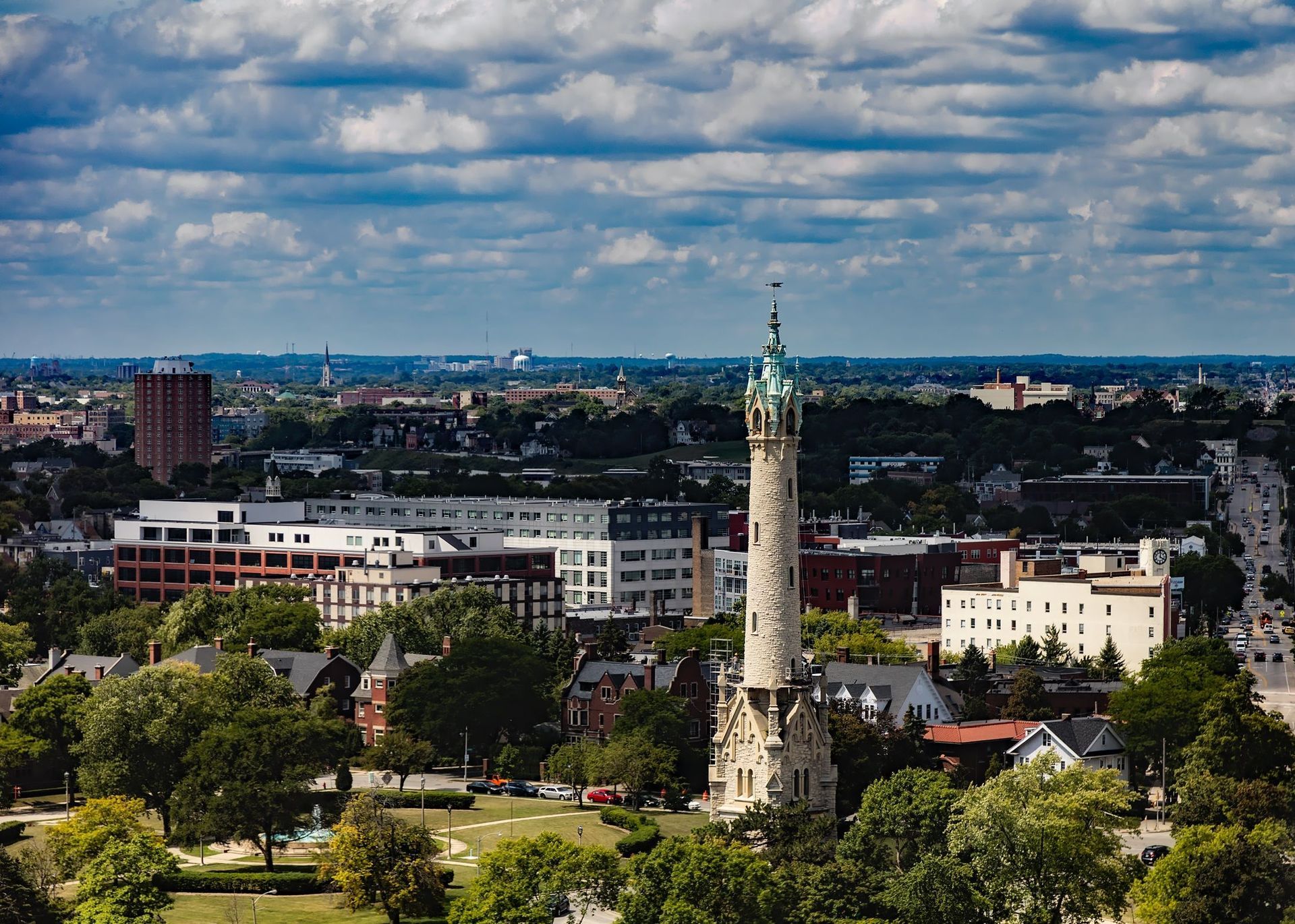 City skyline across a body of water under a blue sky with scattered clouds