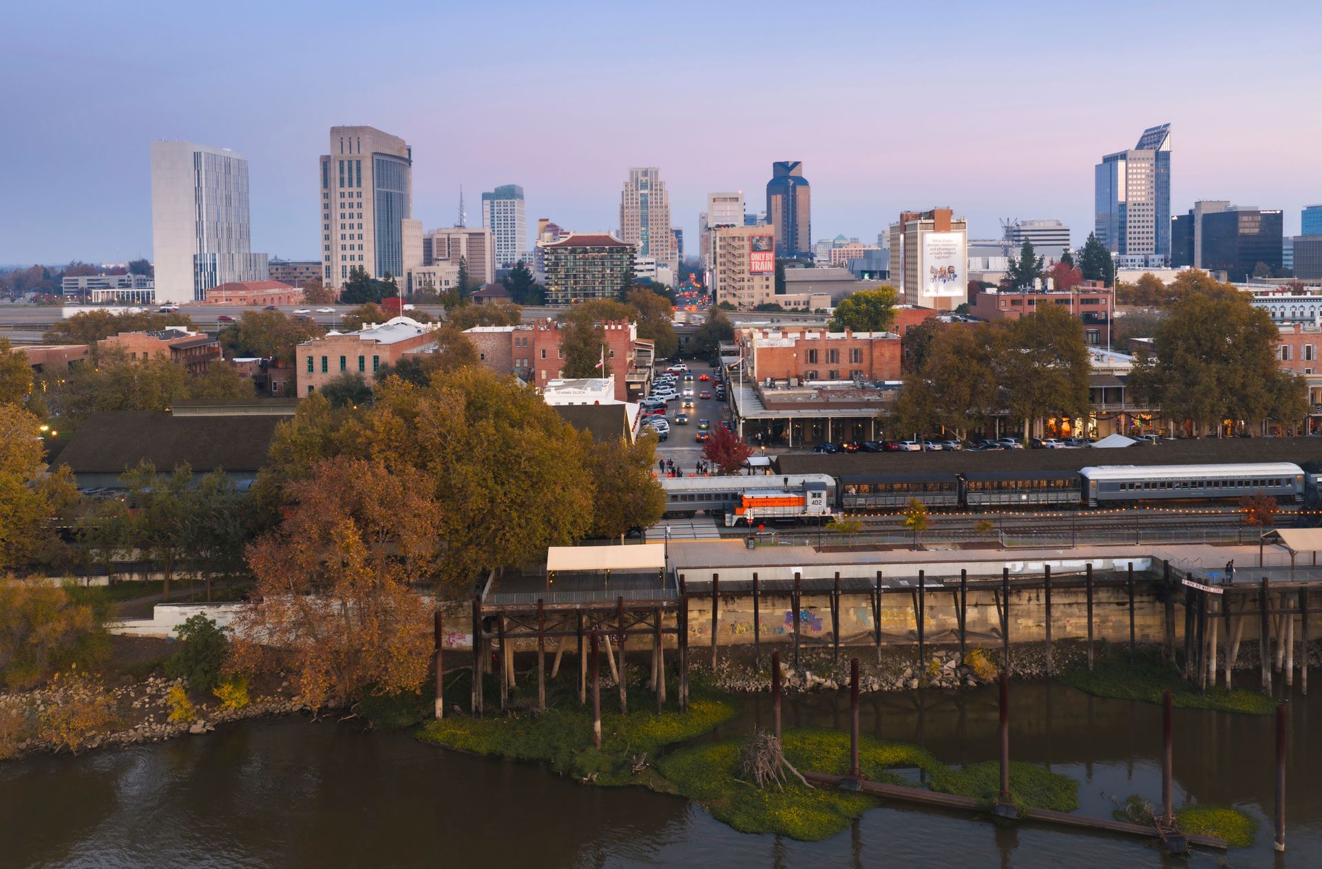 City skyline at sunset with power lines and utility poles in the foreground