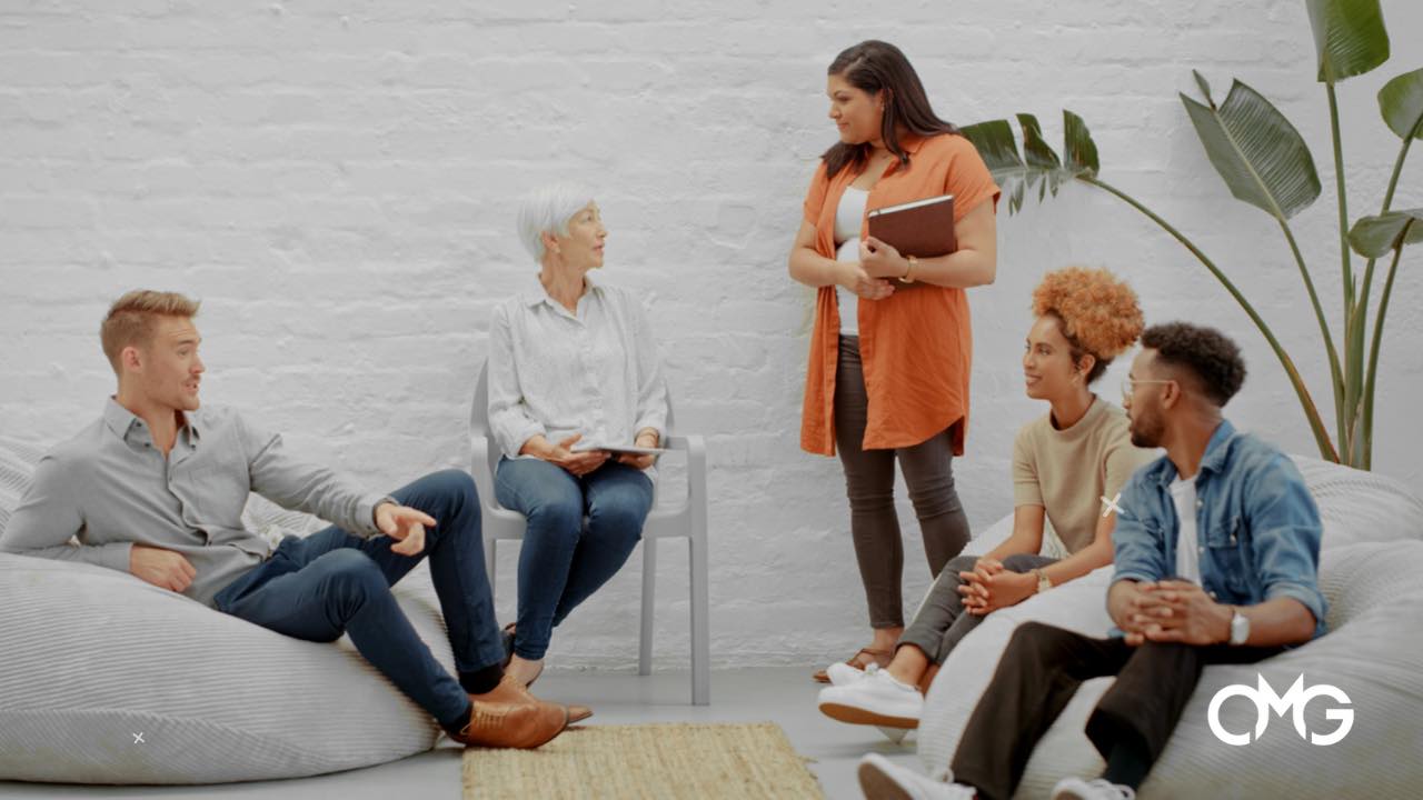 A group of people are sitting on bean bags in a room talking to each other.