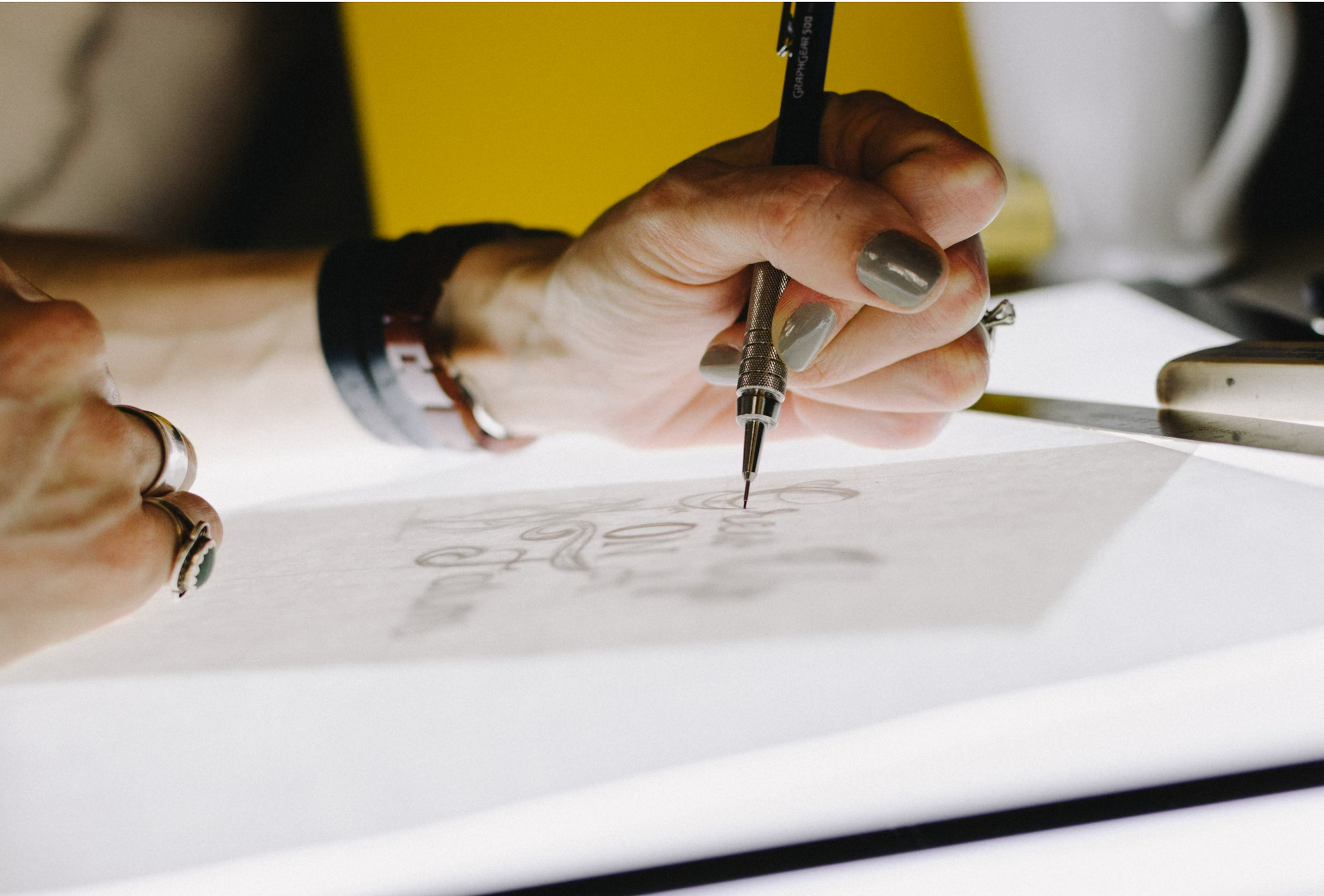 A close-up of a person designing a logo on a tracing paper.