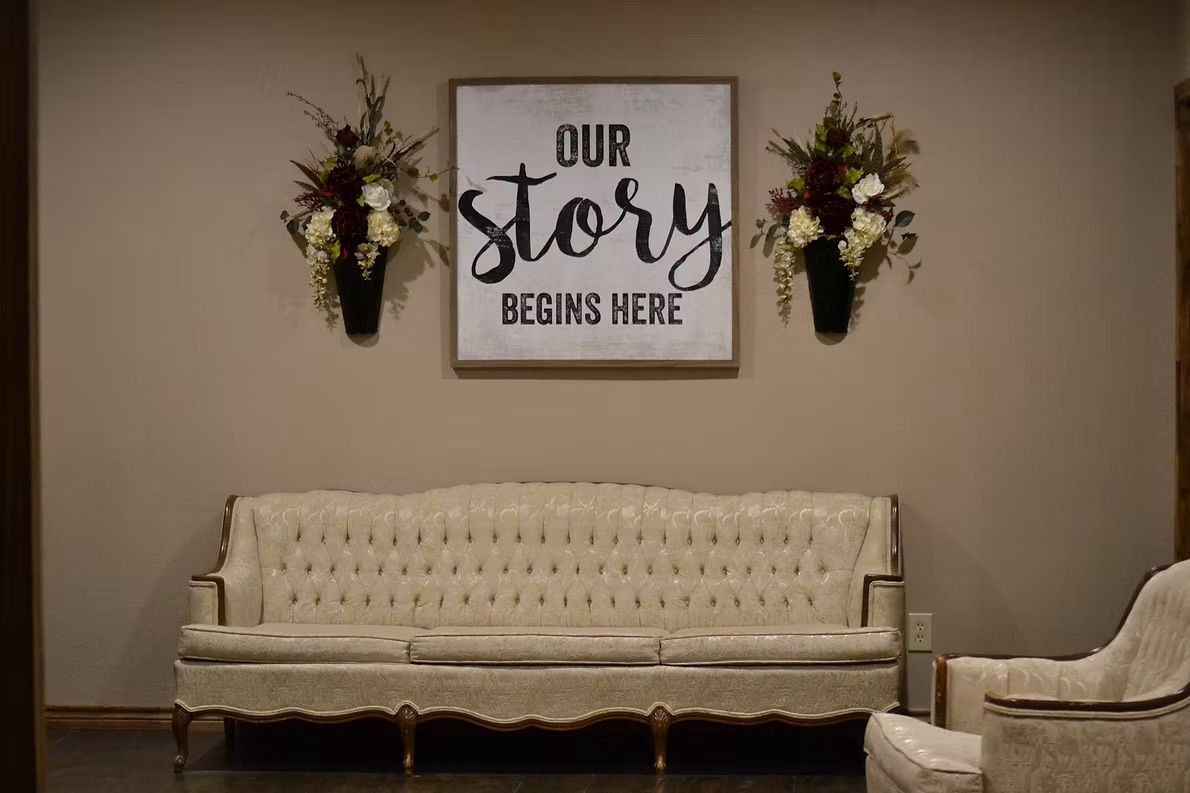A beige couch and chair beneath a framed sign that reads 