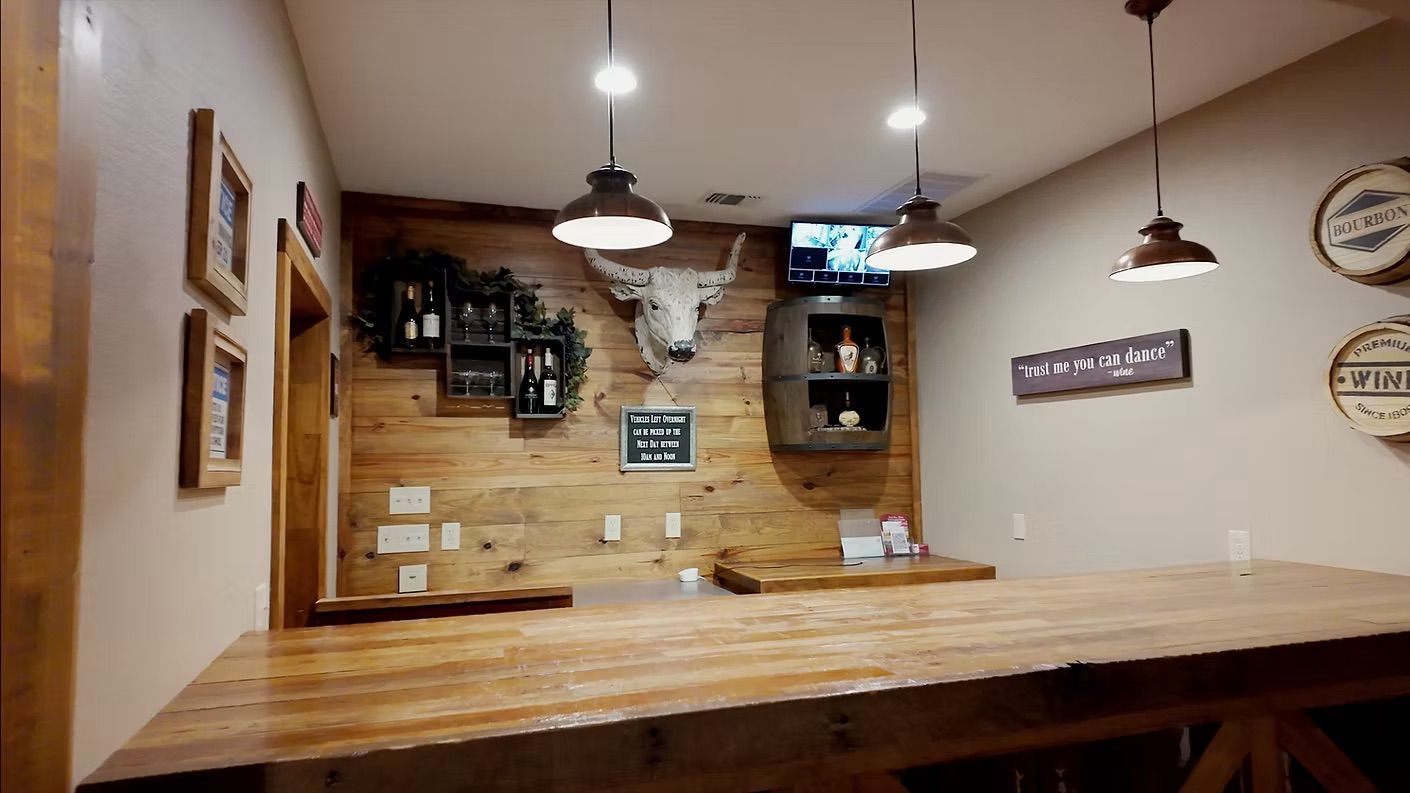 Interior view of a rustic bar with a wooden counter, decorative accents, and overhead lighting.