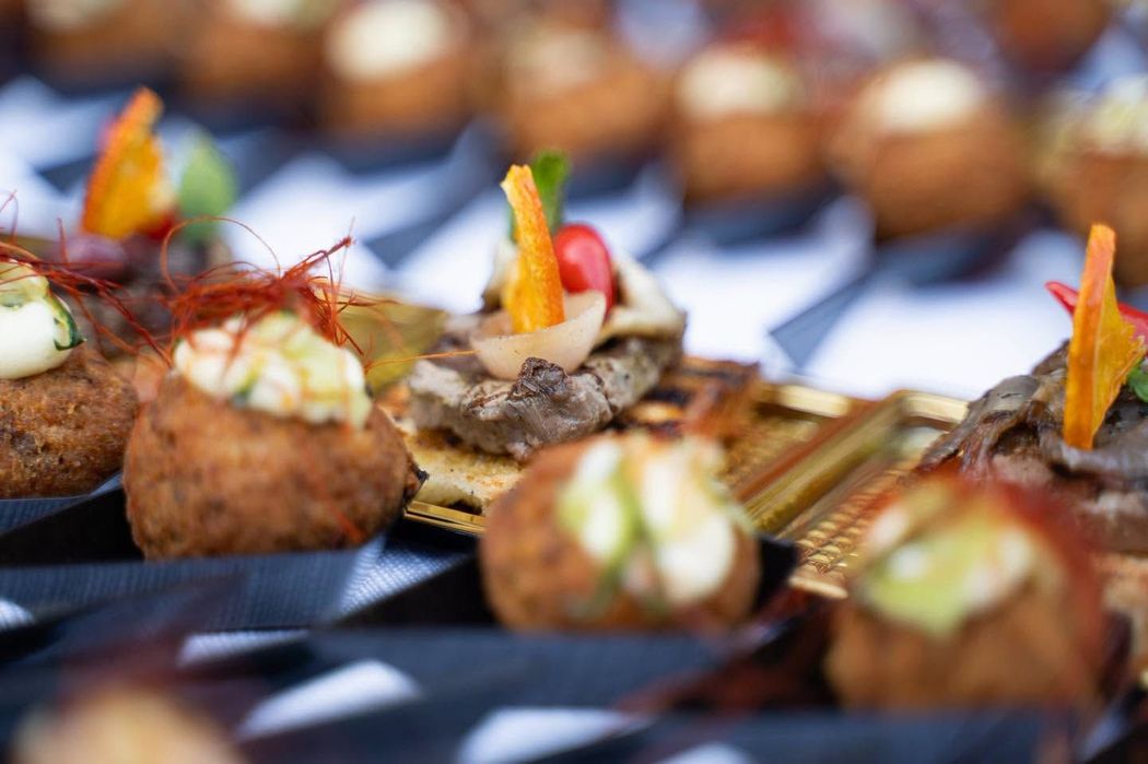 Assortimento di antipasti gourmet su un vassoio, guarniti con decorazioni colorate e spiedini.