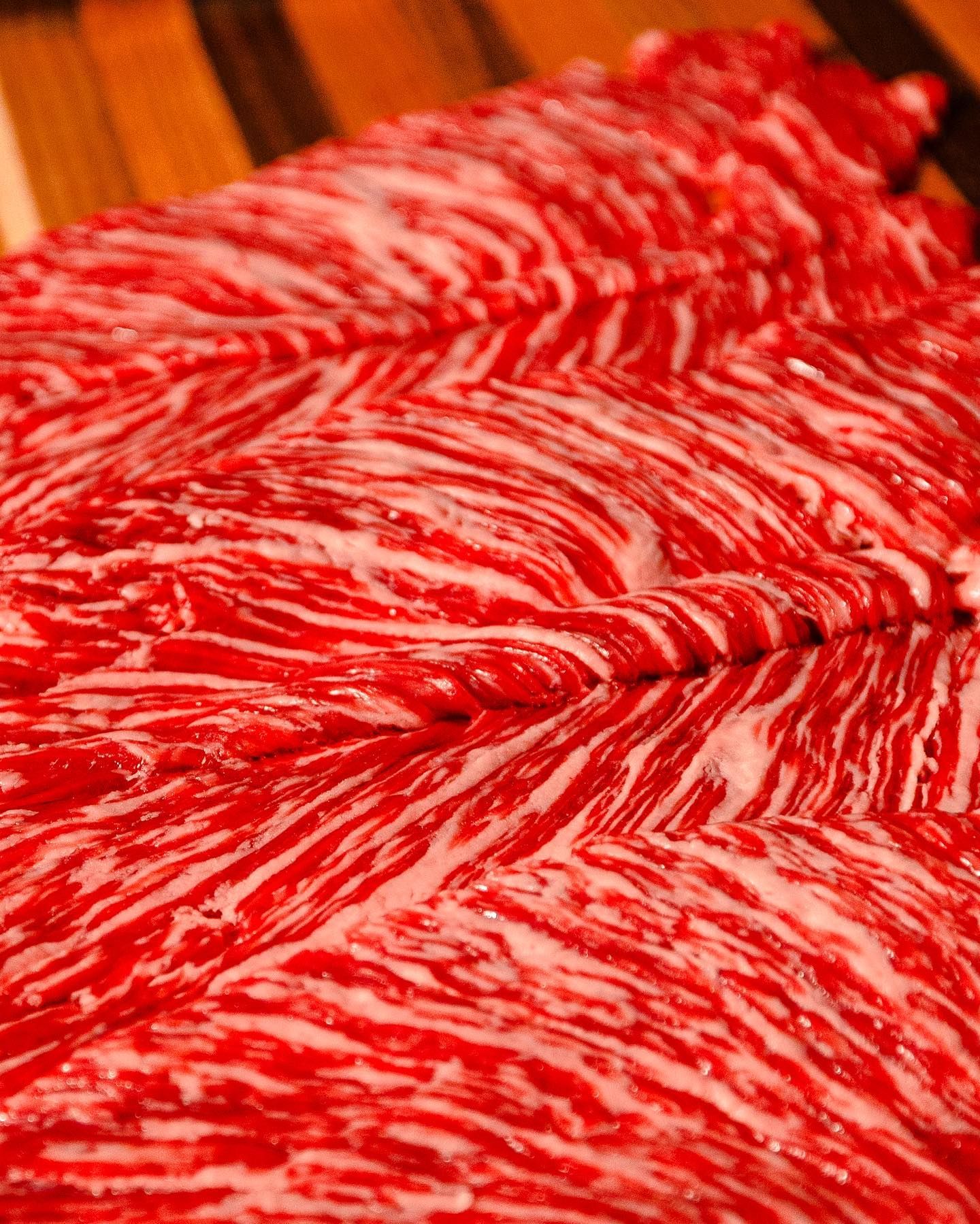 Close-up of marbled red and white raw meat on a wooden surface