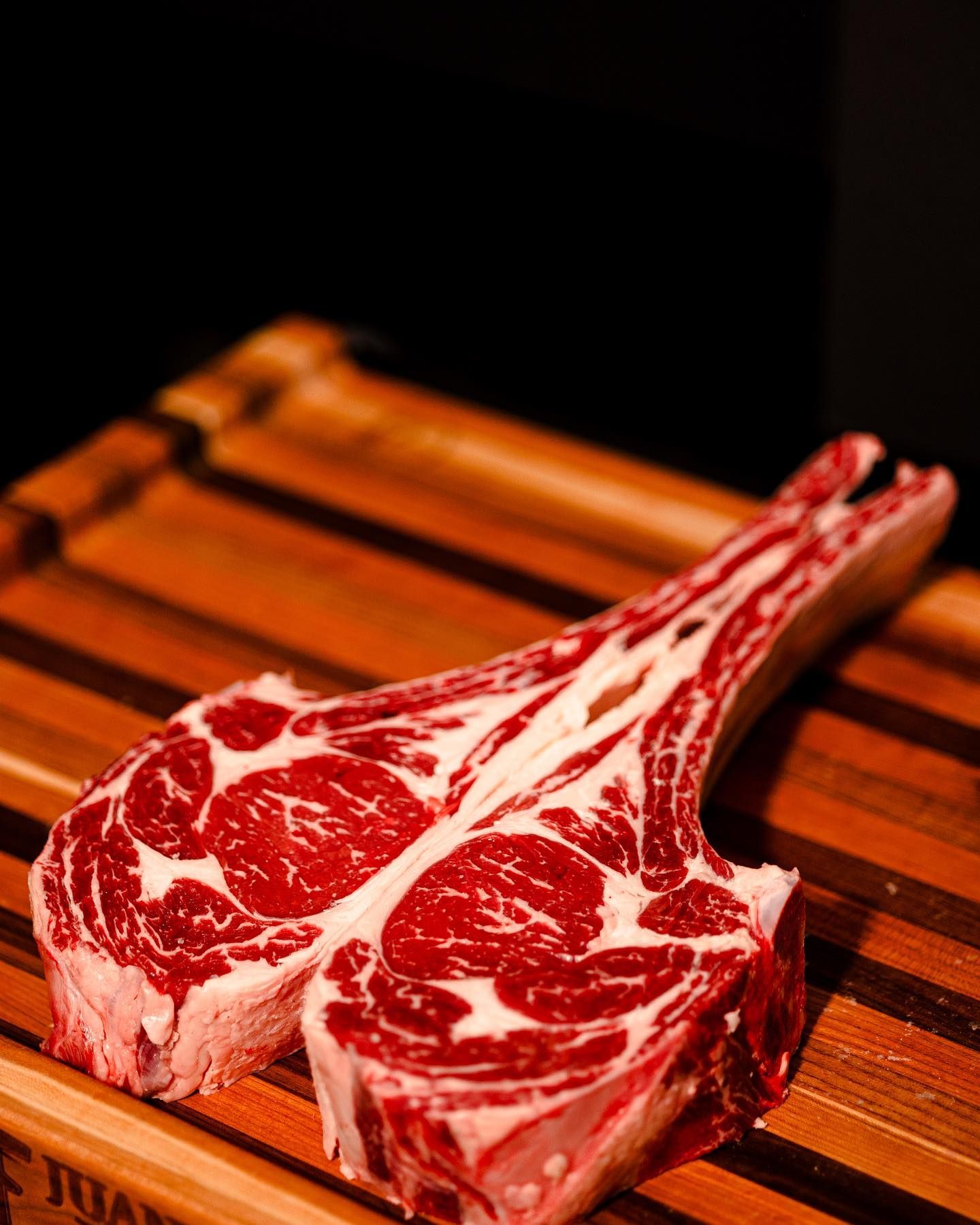 Raw marbled tomahawk steak on a wooden cutting board