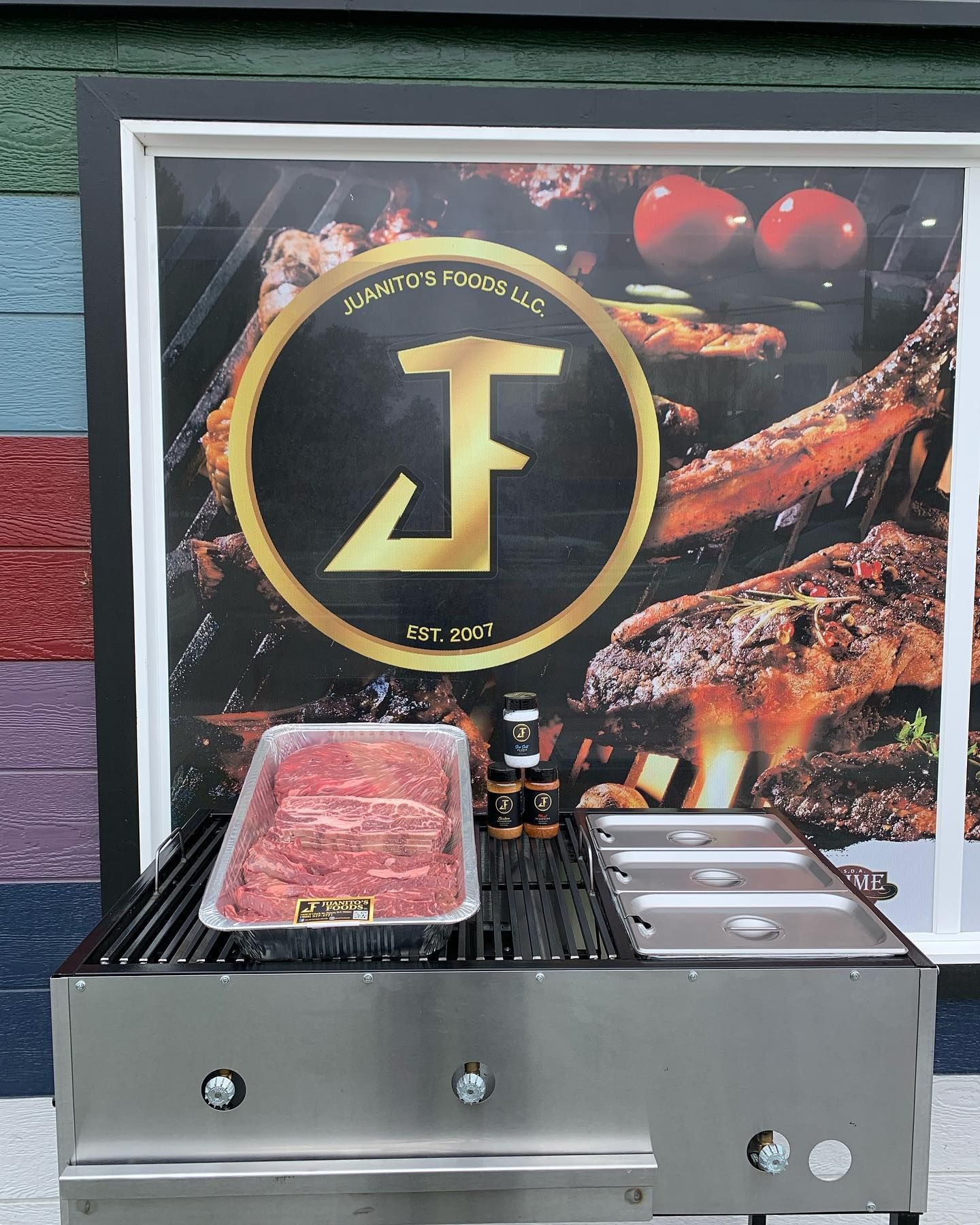 Steak grilling on a stainless tabletop grill before a branded food display backdrop