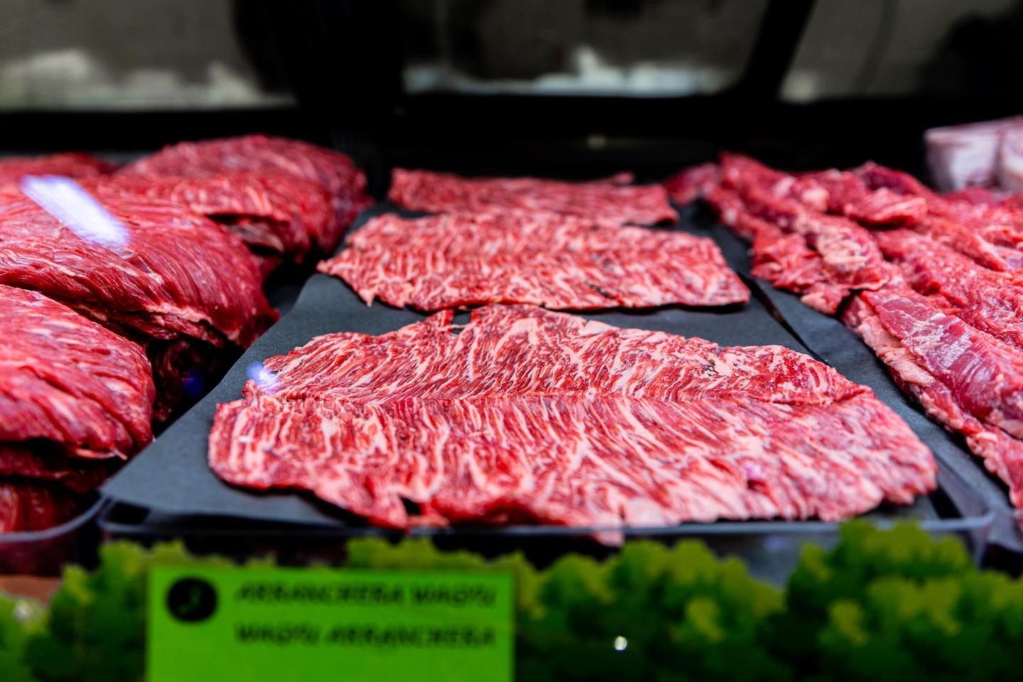Raw beef steaks displayed on a market counter with a price tag and lettuce garnish