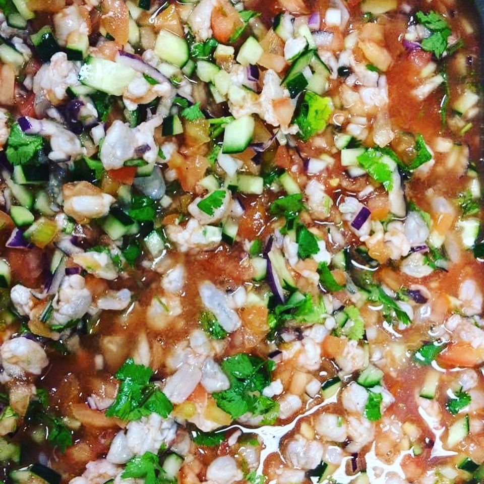 Close-up of chopped onions, herbs, and tomatoes in a red sauce or salsa mixture