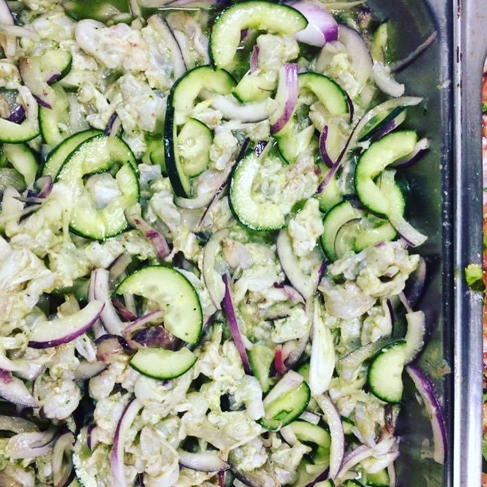 Tray of sliced cucumbers and red onions mixed with a creamy dressing or marinade