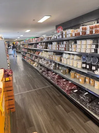 A grocery store aisle with shelves of packaged foods and jars, seen from a low angle under bright ceiling lights
