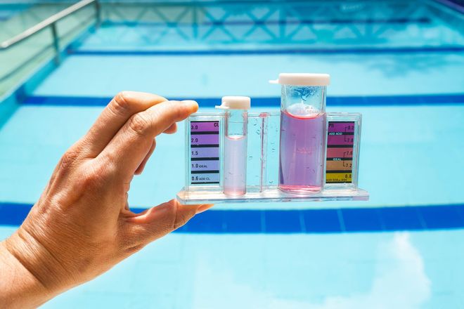 Pool maintenance service technician testing pool water chemistry with professional test kit.