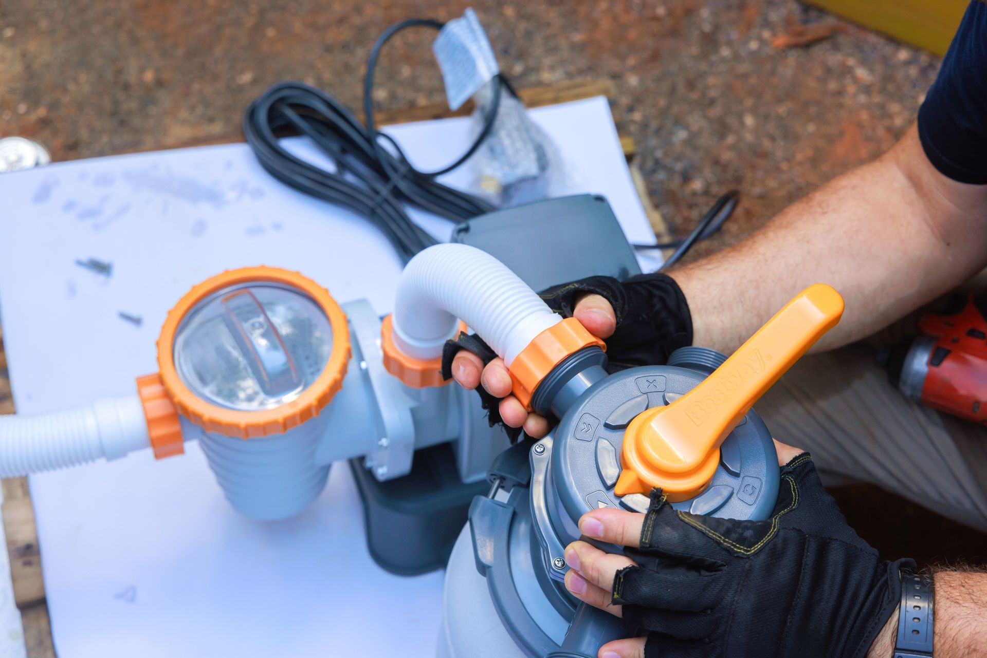 A man is working on a swimming pool filter.