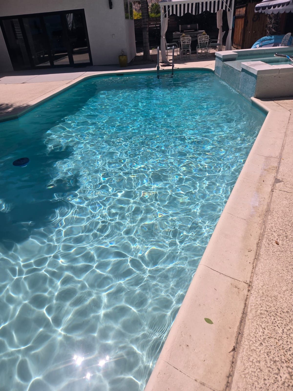 A large swimming pool with a white house in the background.