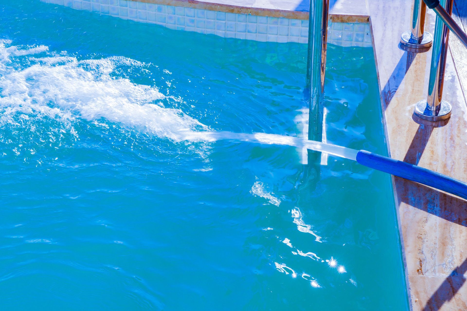 A person is cleaning a swimming pool with a vacuum cleaner.