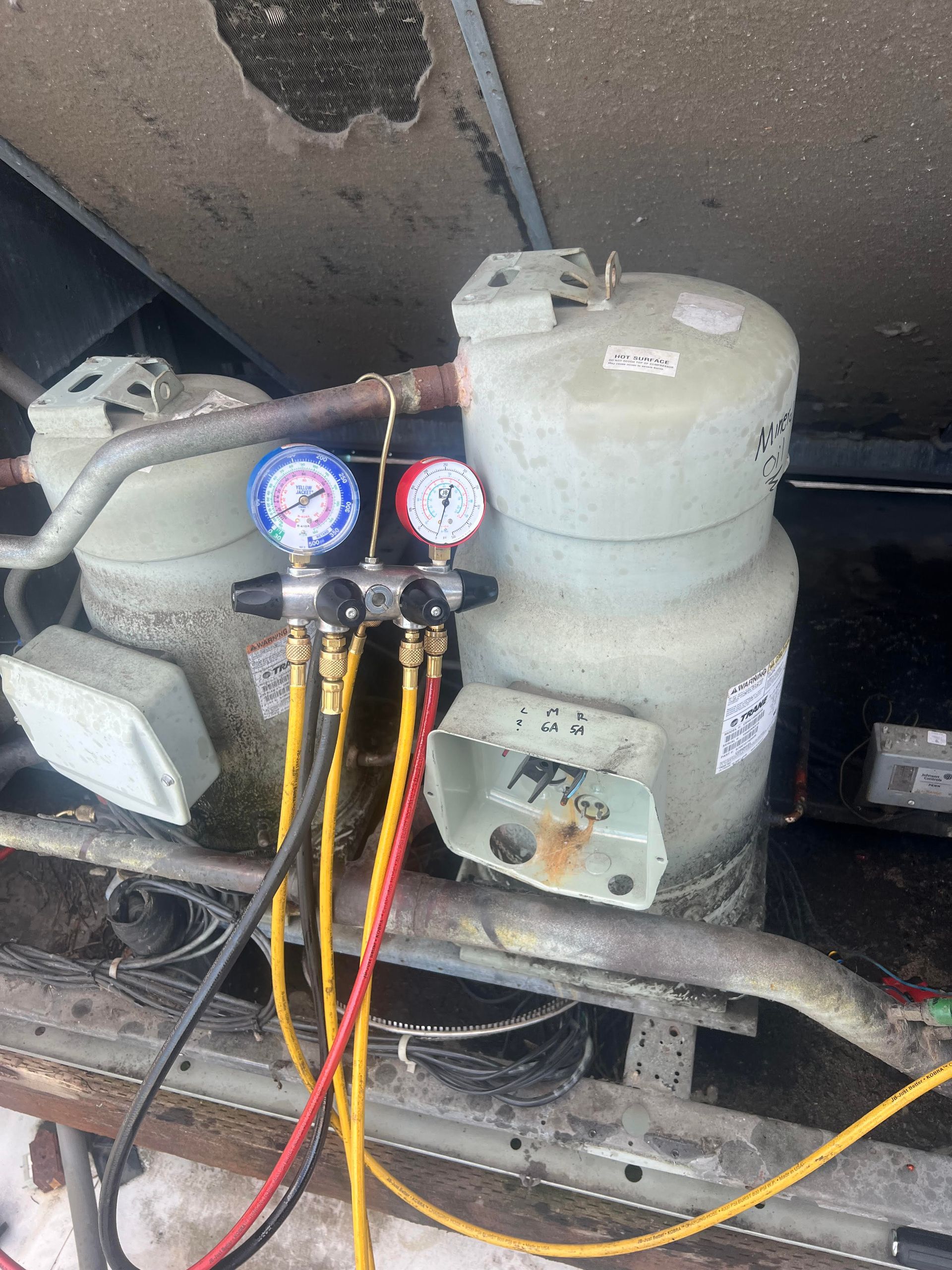 A Pro Temp technician is kneeling down and working on an air conditioner.