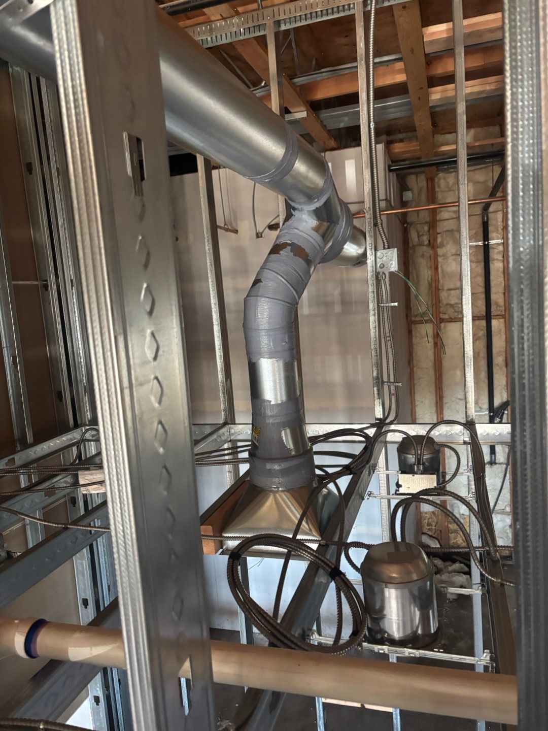 Silver HVAC ductwork and metal framing in an unfinished building interior.