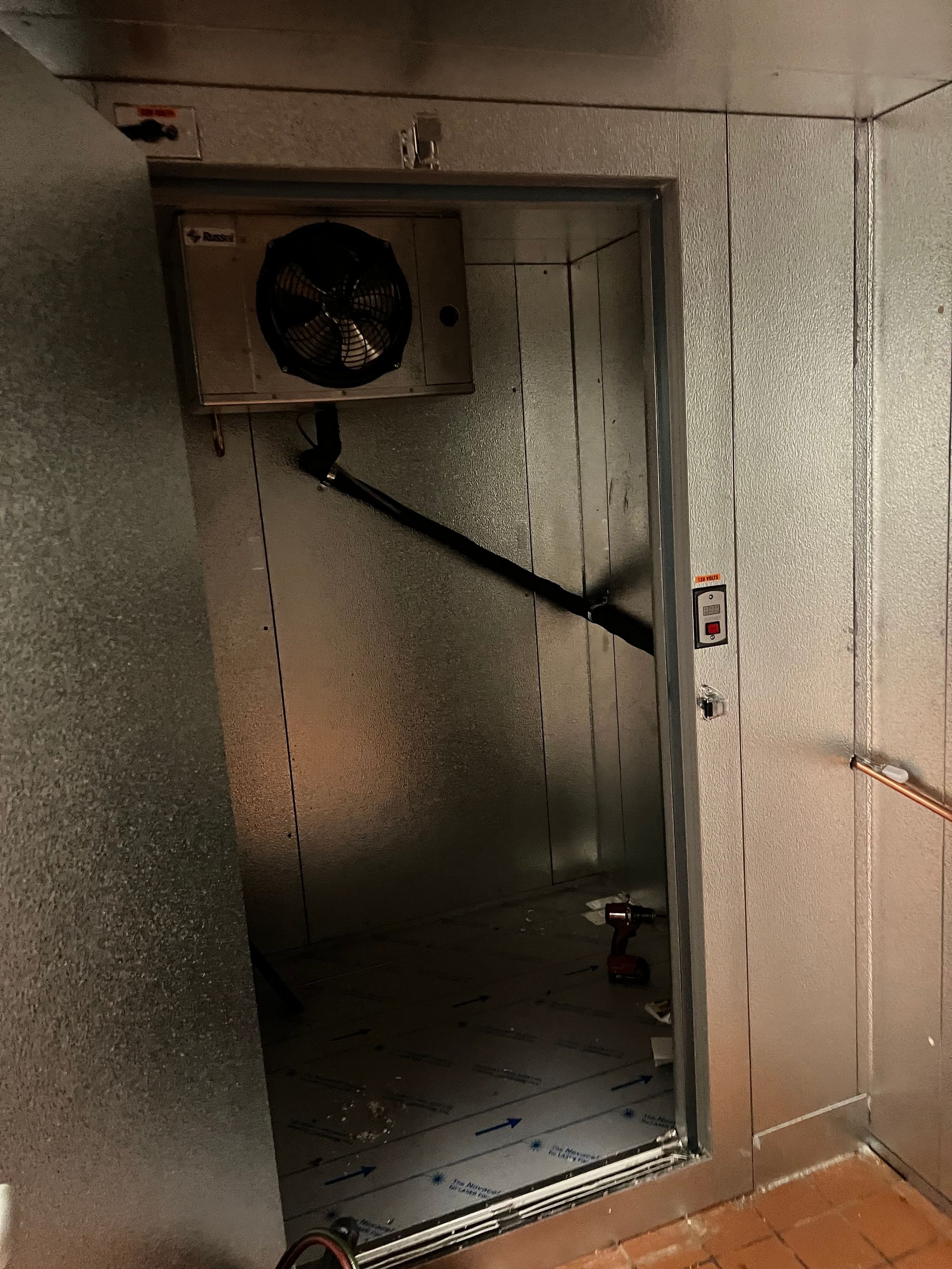 Open industrial metal chamber with a fan mounted at the top and a dark interior opening