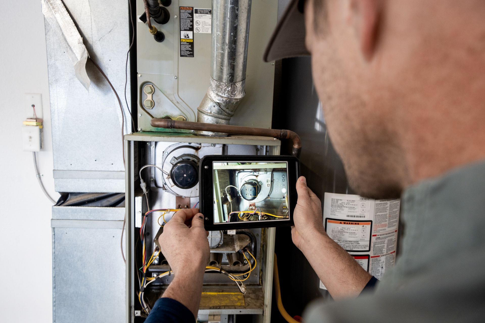 HVAC technician performs furnace maintenance on residential heating system during seasonal tune-up.