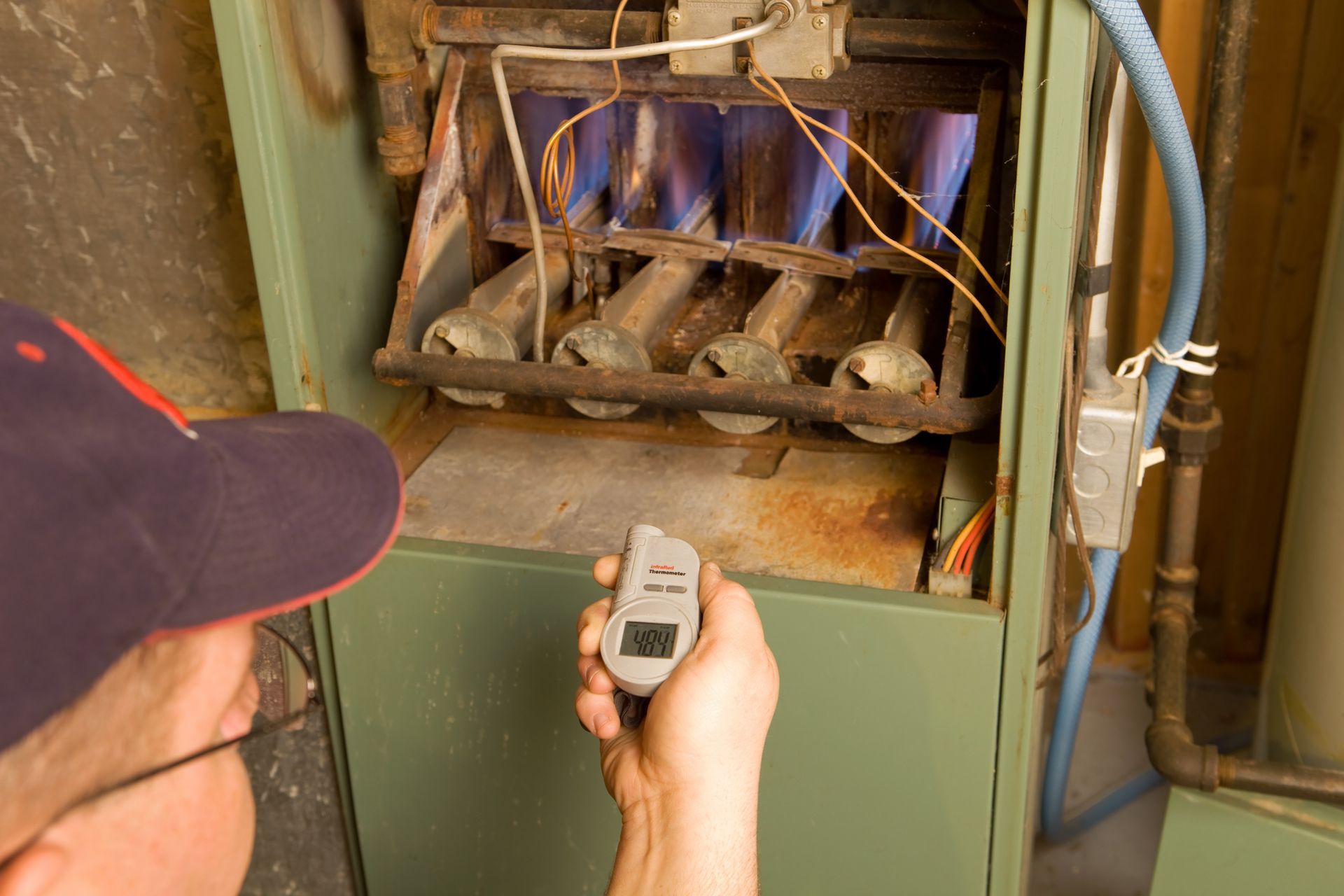 HVAC technician inspecting an older residential furnace to determine if replacement.