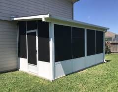 San Antonio screen room in Stone Oak with a modern insulated roof and dark framing that complements the home’s stucco exterior.