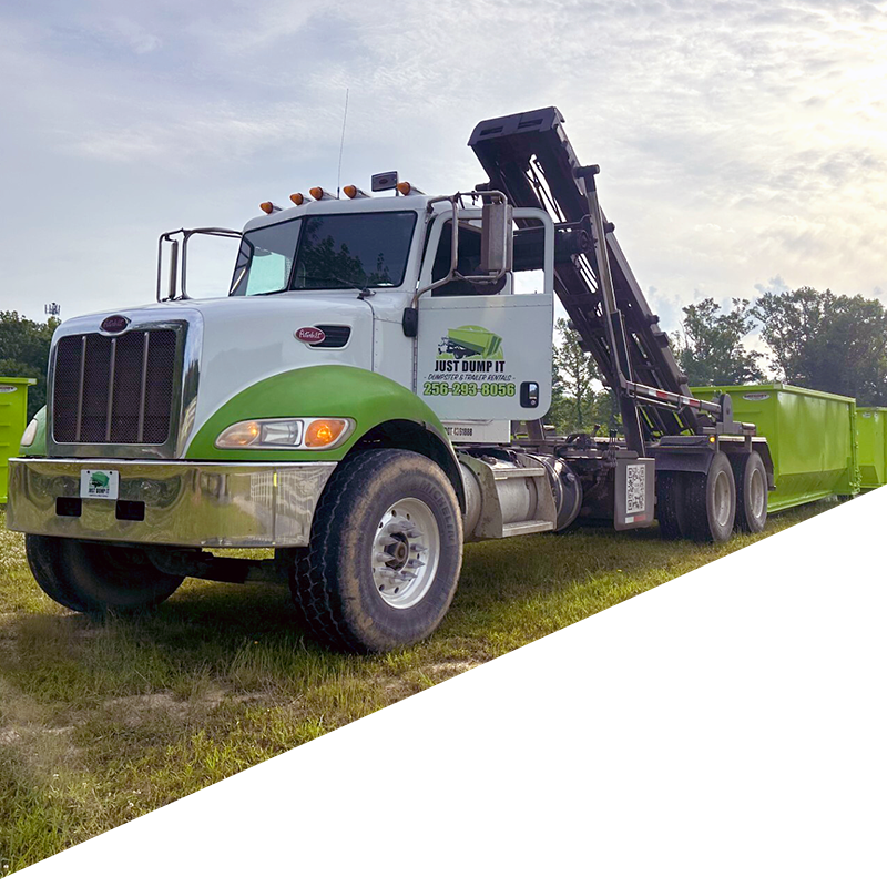 White tow truck with a black lift arm parked on grass in a green field under a cloudy sky