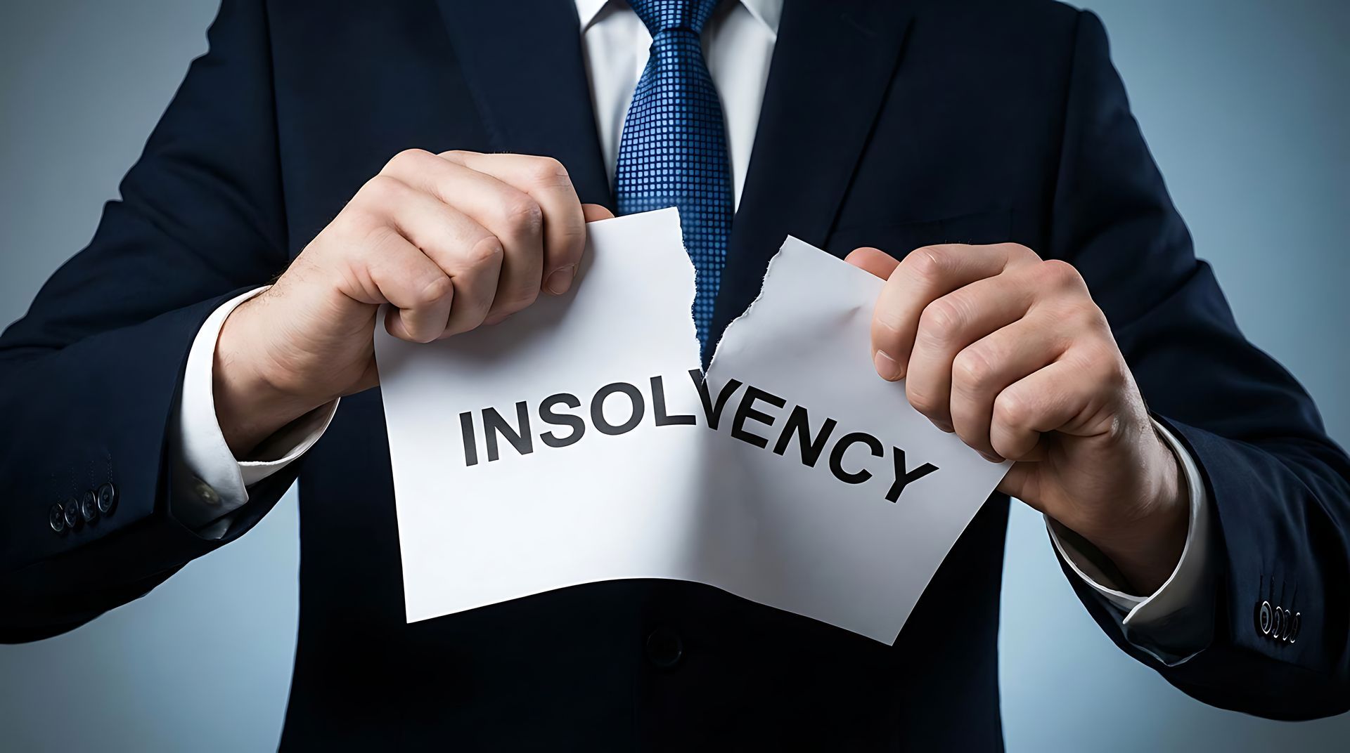 Businessman tearing 'Insolvency' paper, symbolizing financial freedom and resolution from debt crisi