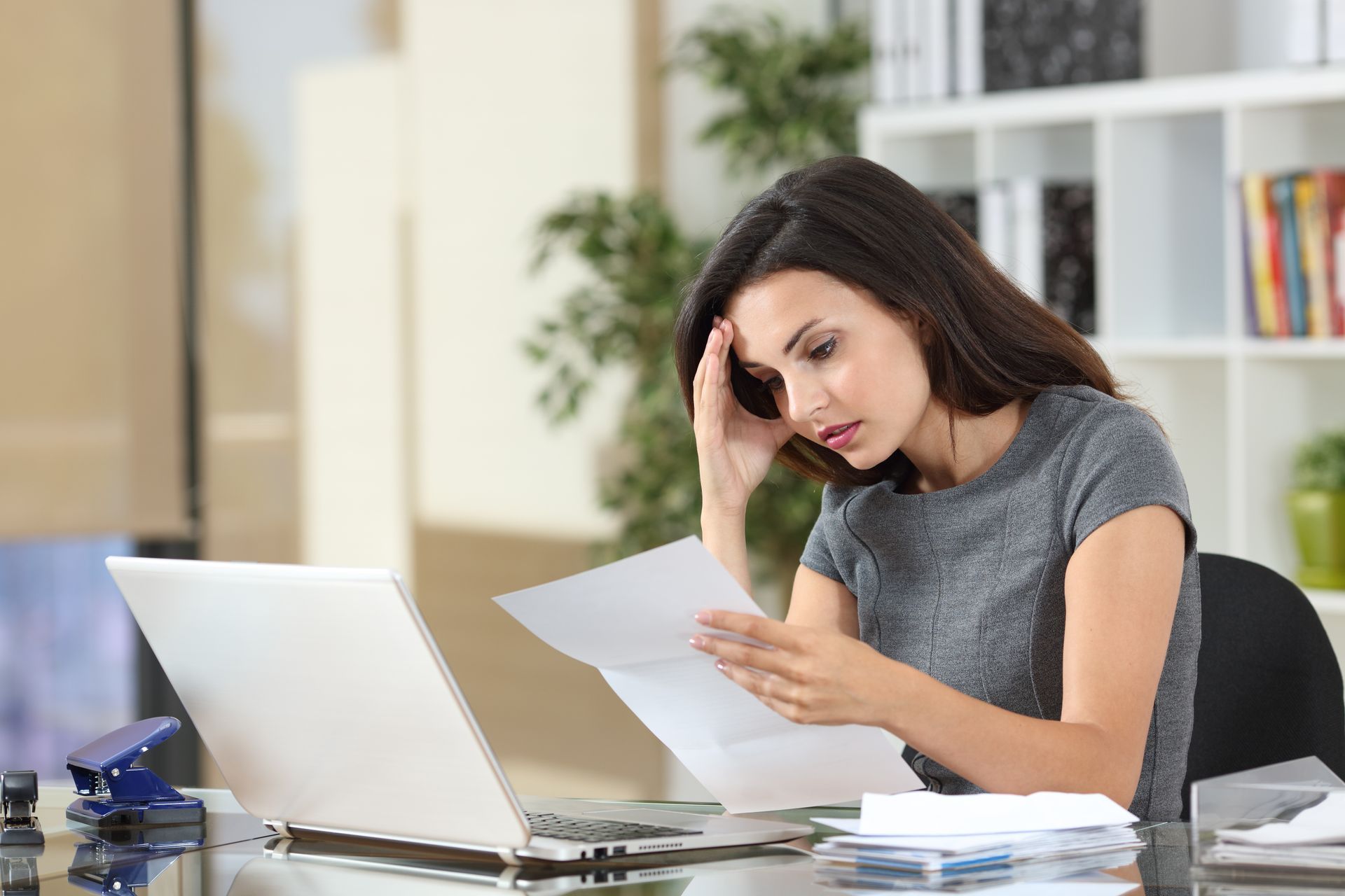 Worried business owner looking at documents on her desk.