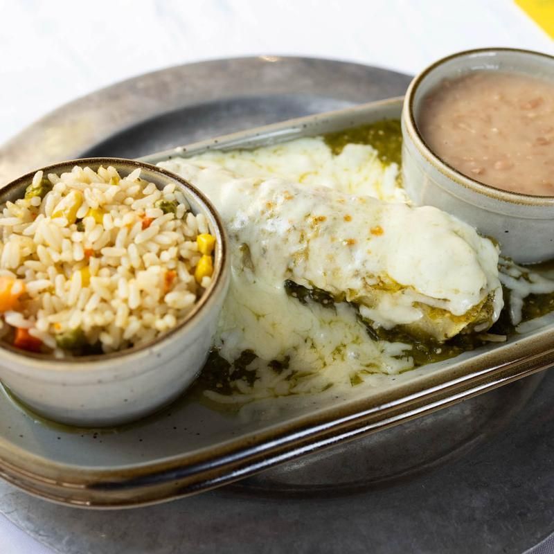Steamed fish in green sauce with rice and a creamy side on a metal tray