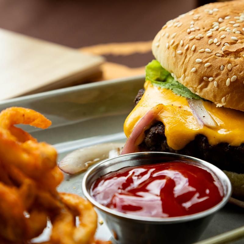 Cheeseburger with melted cheddar, curly fries, and ketchup on a plate