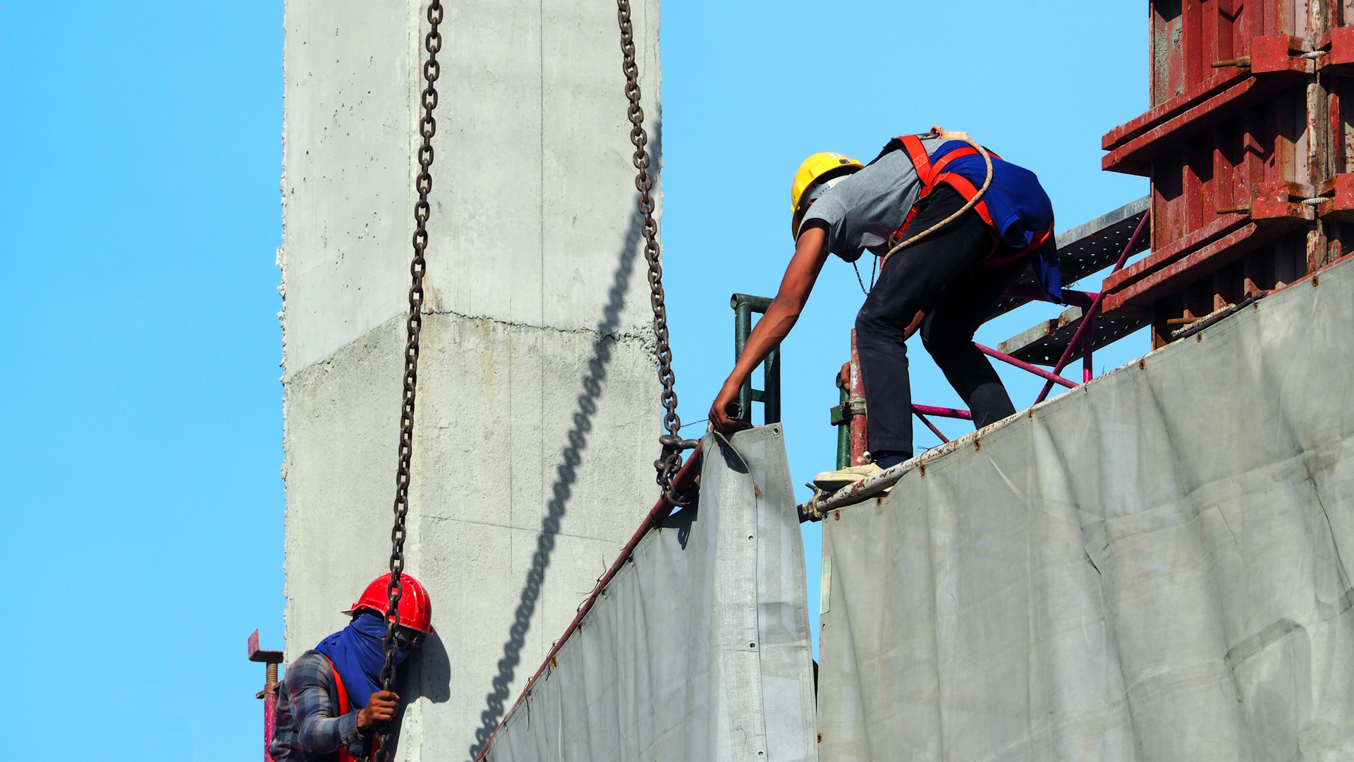Workers installing plywood flooring on a wooden frame at a construction site