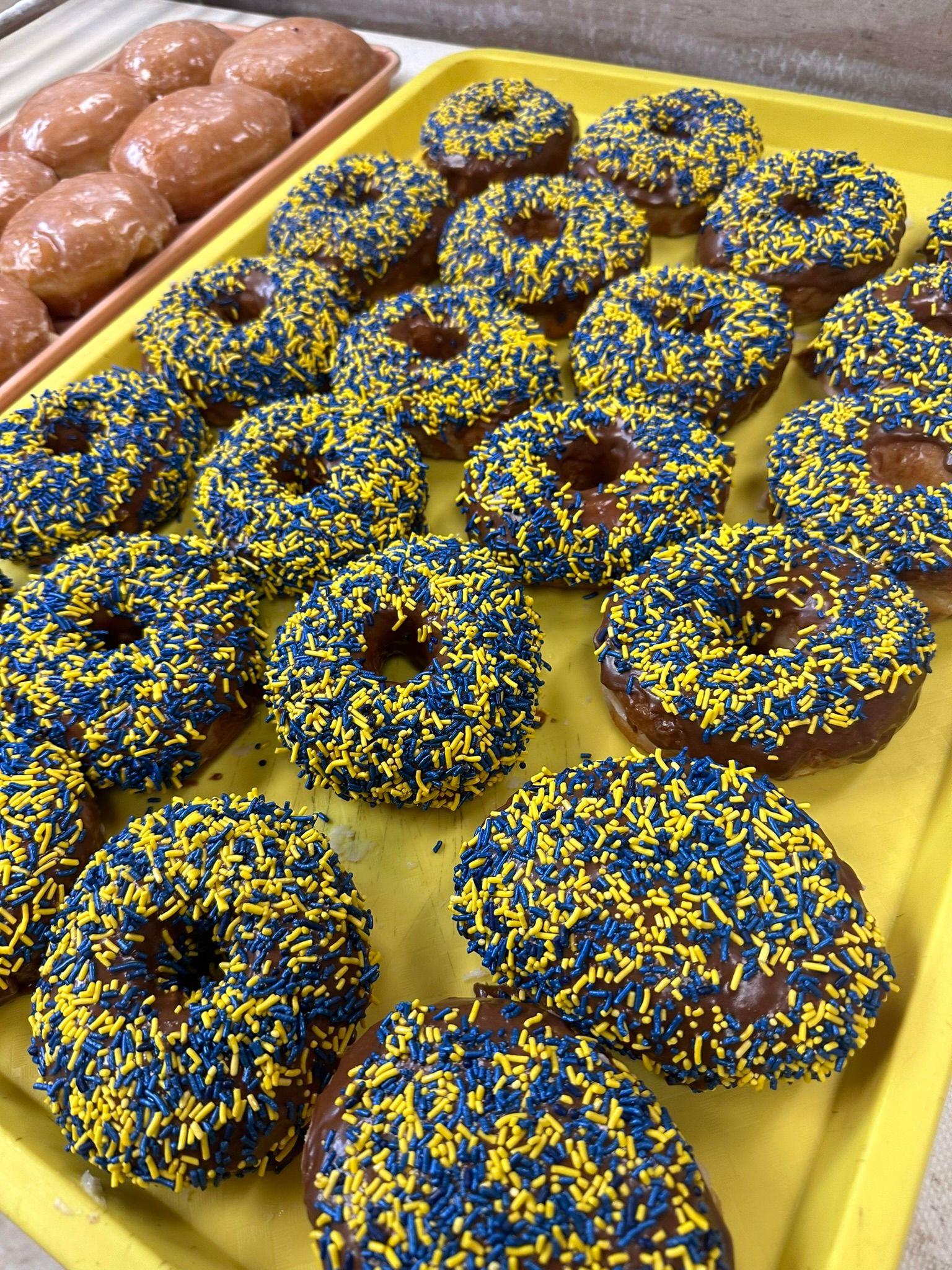 a tray of donuts with blue and yellow sprinkles