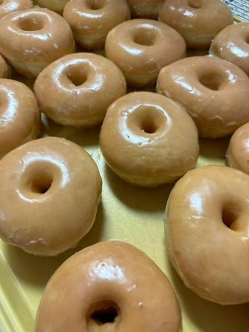 a bunch of glazed donuts are sitting on a yellow plate .