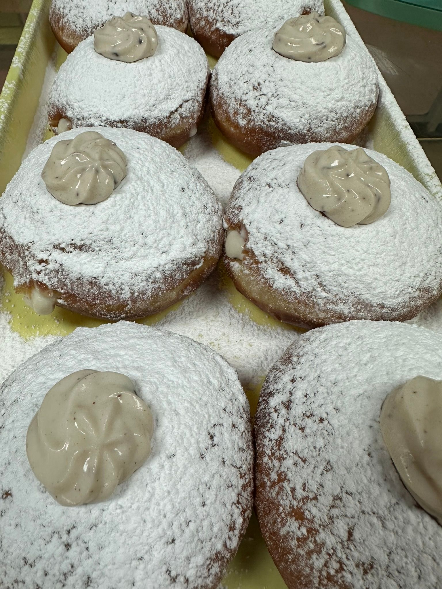 a bunch of donuts with powdered sugar on top are on a tray .