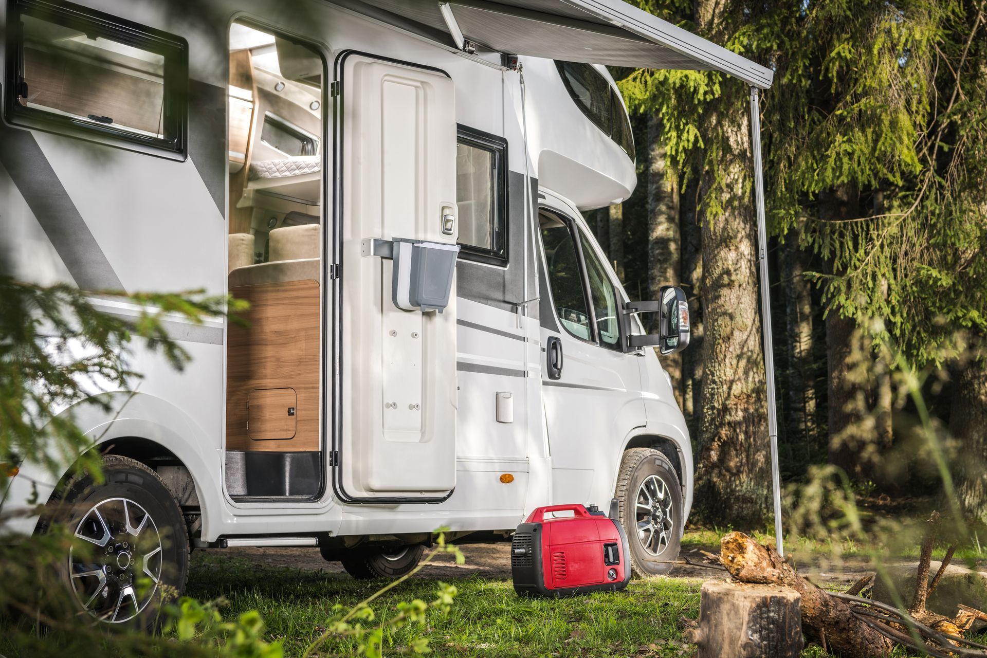 White camper van parked in a wooded campsite with an open door and red cooler beside it