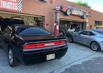 A black dodge challenger is parked in front of a garage.