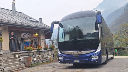 Autobus blu parcheggiato accanto a un edificio in pietra in un contesto montano.