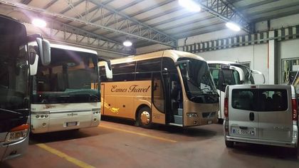 Autobus blu parcheggiato davanti a un edificio storico illuminato al crepuscolo.