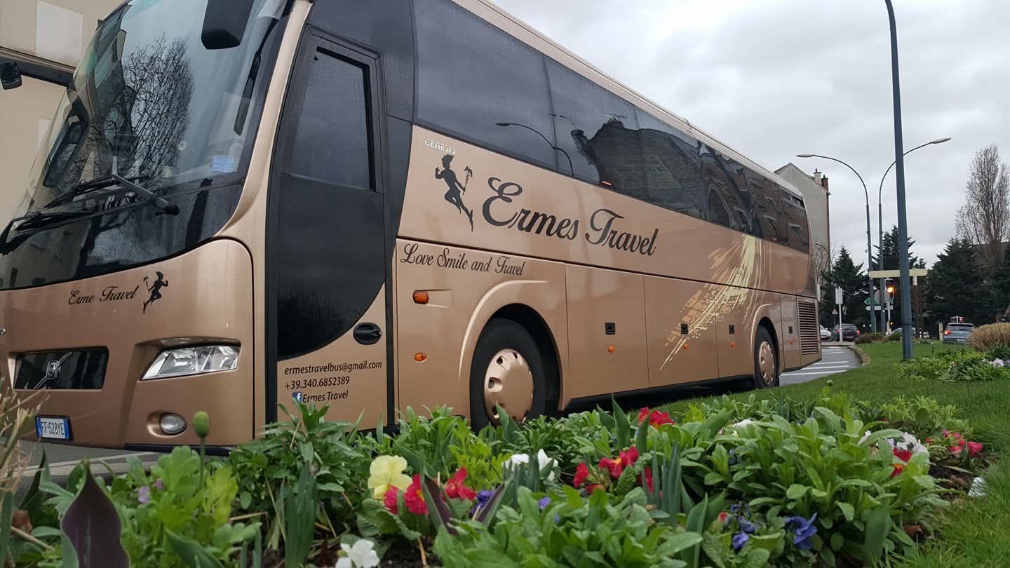 Autobus blu parcheggiato davanti a un edificio storico illuminato al crepuscolo.