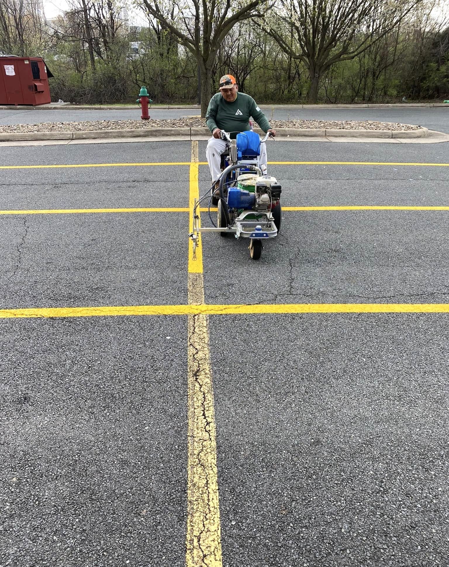 Image of a person repainting a parking lot with yellow lines.
