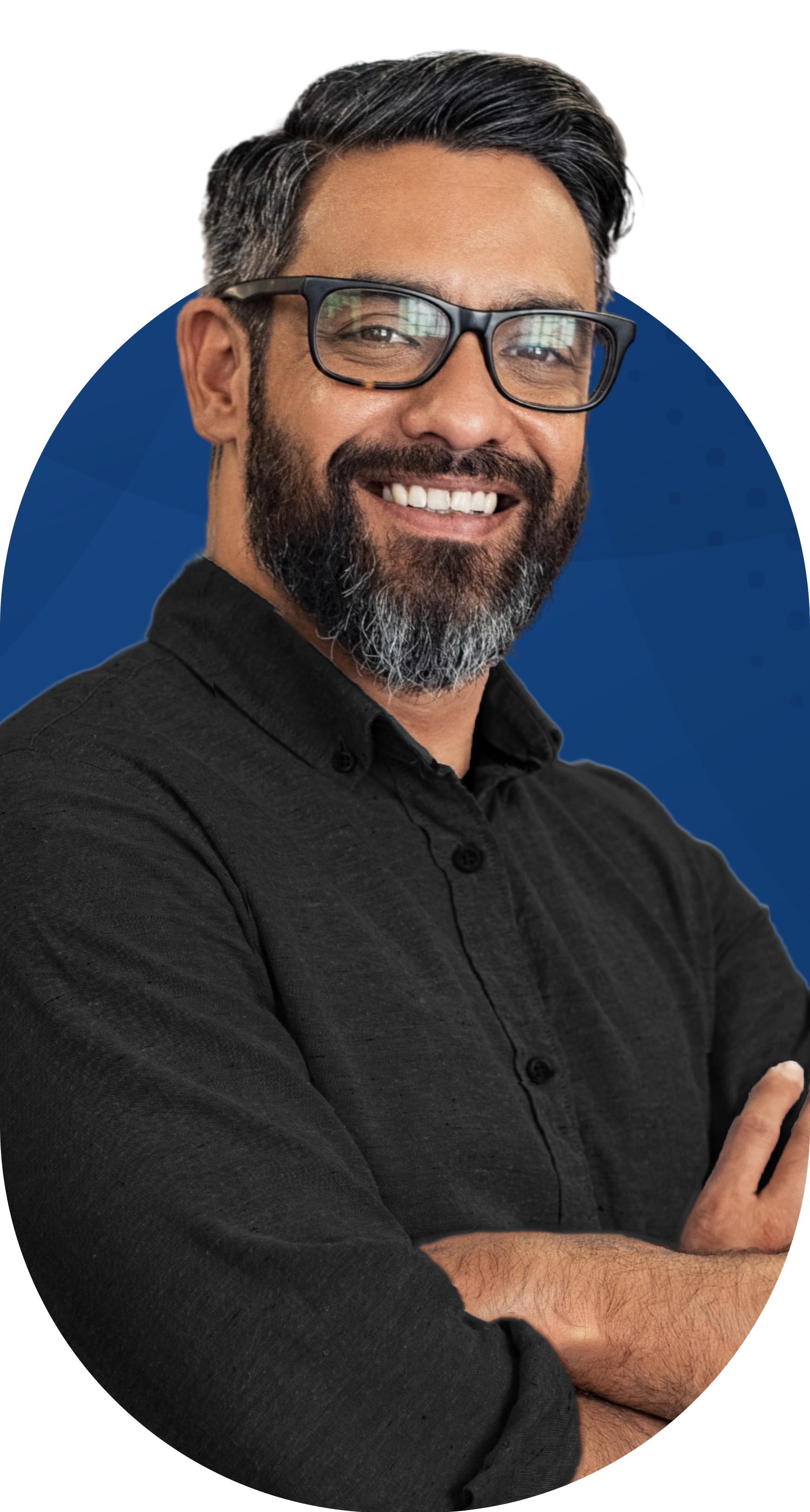 Man with glasses and beard smiles, arms crossed, wearing a black shirt, against a blue background.