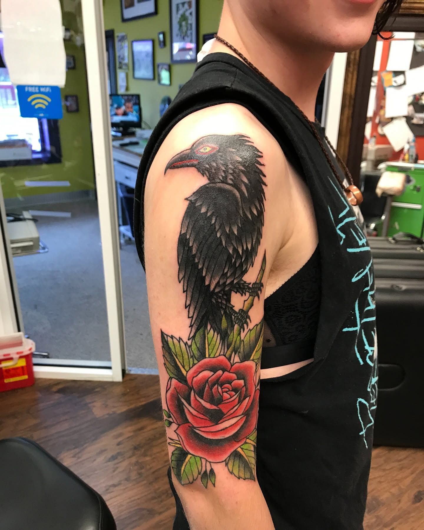 Tattoo by Eric Estrada at The Widow's Son Tattoo Co. in Gilbertsville, PA — a raven perched on a red rose, in traditional style on an upper arm