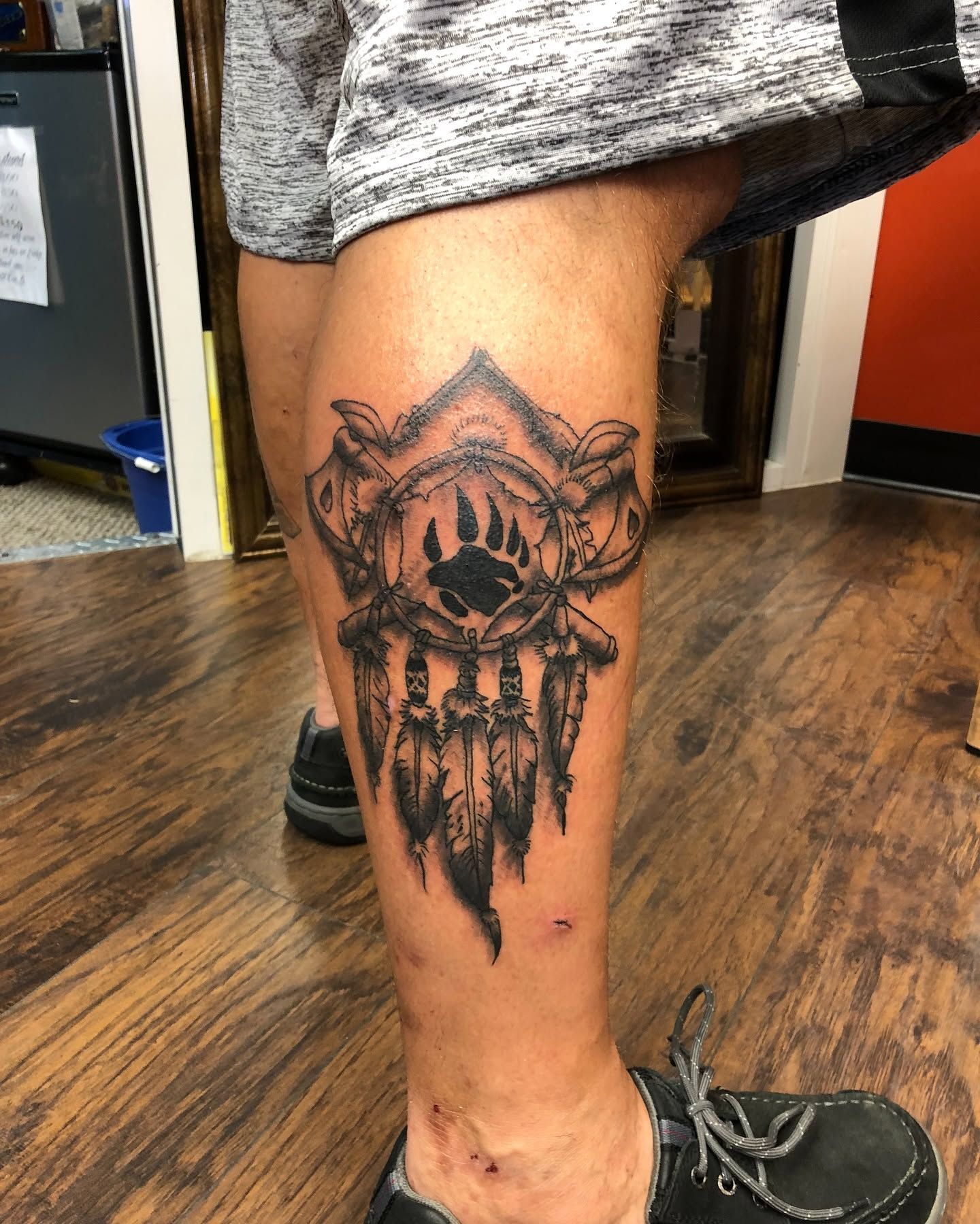 Tattoo by Eric Estrada at The Widow's Son Tattoo Co. in Gilbertsville, PA — a black and grey demon mask down a shin