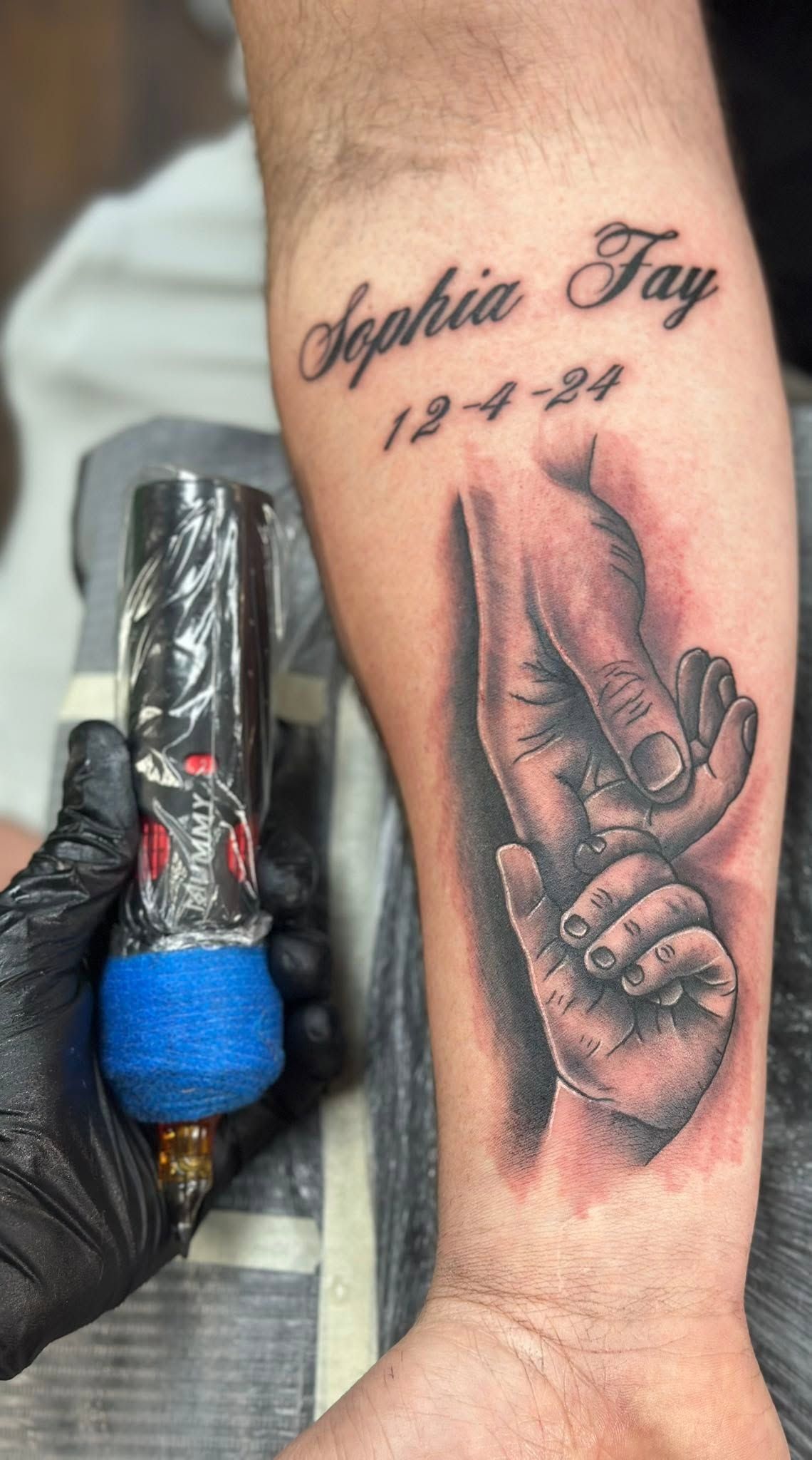 Tattoo by Eric Estrada at The Widow's Son Tattoo Co. in Gilbertsville, PA — black and grey praying hands with a name and a date on a forearm