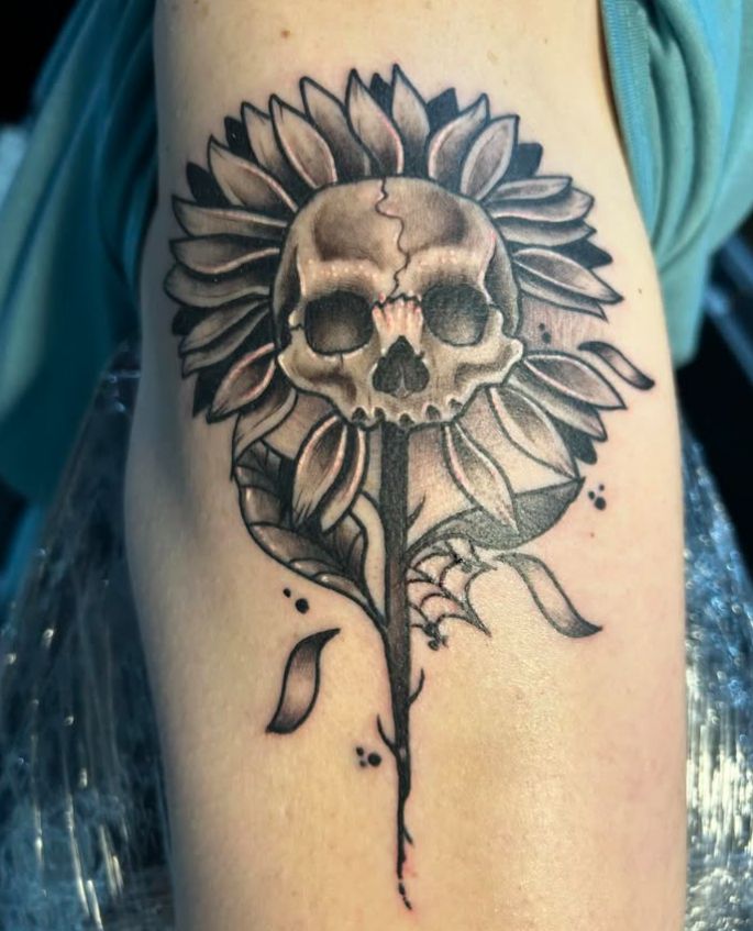 Tattoo by Tom Kelly at The Widow's Son Tattoo Co. in Gilbertsville, PA — a skull inside a sunflower, in black and grey