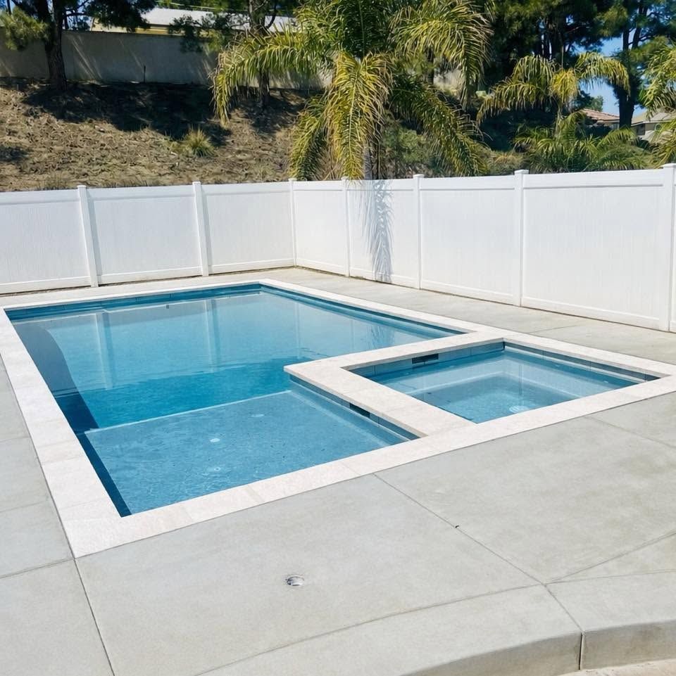 Backyard pool with spa, lounge area, and yellow cabana under a blue sky.