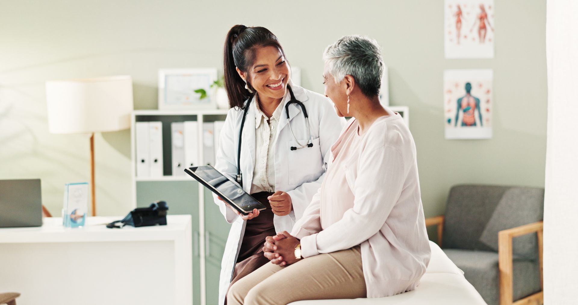 Smiling doctor reviewing a tablet with a senior patient during a local women health care visit Smiling doctor reviewing a tablet with a senior patient during a local women health care visit