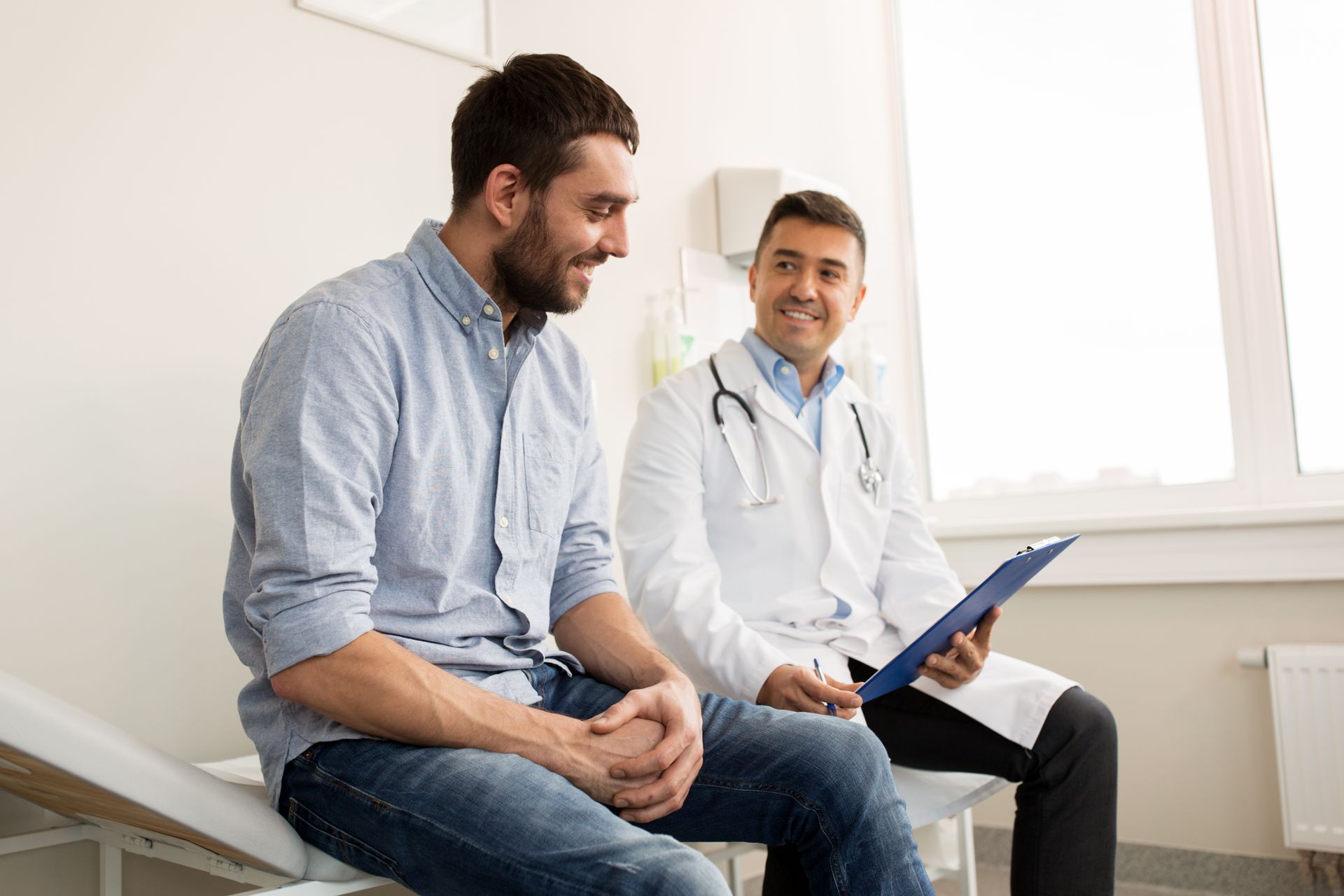 Men health care physician checking a male patient’s blood pressure during an annual wellness exam.